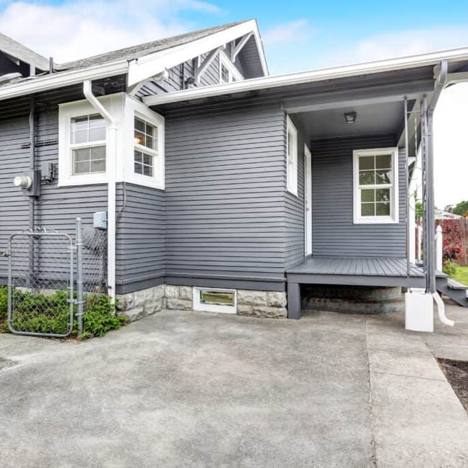 backyard house with siding trim, wooden floor porch, concrete walkway.